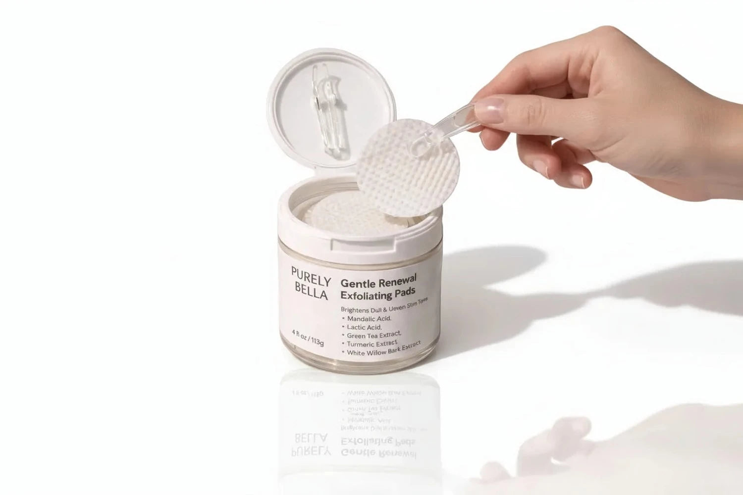 Hand holding a container of 'Purely Gentle Renewal Exfoliating Pads' with a white background