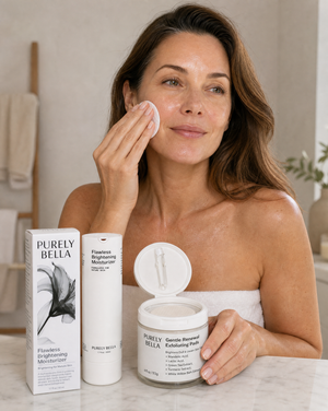 Woman applying facial cream with Purely Bella skincare products on a marble surface.