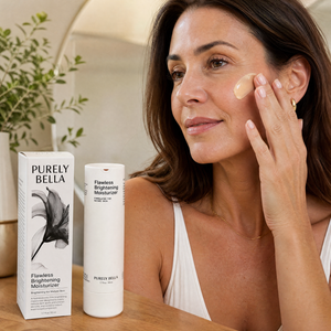 Woman applying facial cream with Purely Bella products on a table.