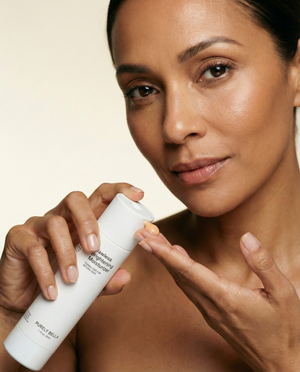 Woman holding a skincare product with a neutral background