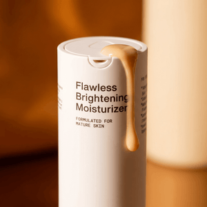 Flawless Brightening Moisturizer cream texture spilling from bottle on warm background