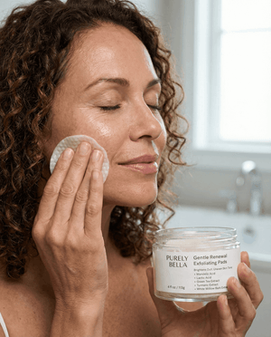 Woman applying facial product to her face with a jar of 'Purely Bella' product in the foreground.