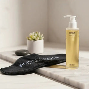 Skincare bottle on a marble surface with a black sock and plant in the background