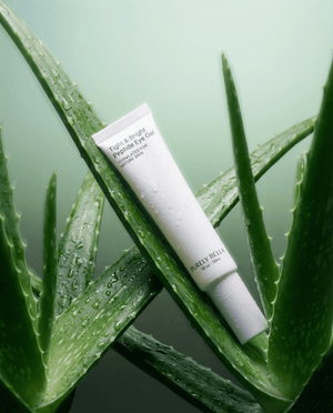 Tube of eye gel on aloe vera leaves with a green background