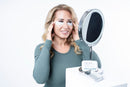Woman in mirror with reusable eye masks - hydrating silicone treatment reduces puffiness