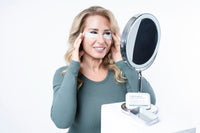 Woman in mirror with reusable eye masks - hydrating silicone treatment reduces puffiness